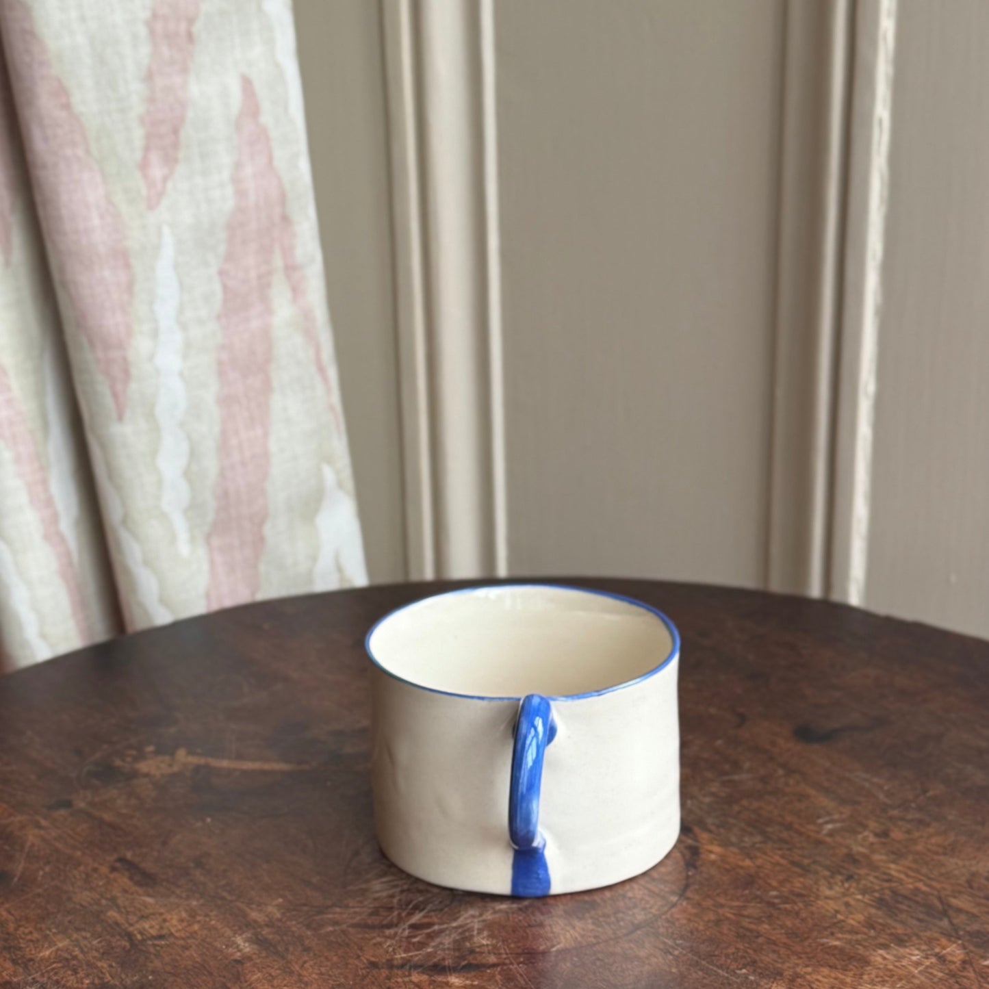 Ceramic handmade stoneware mug with blue rim and handle